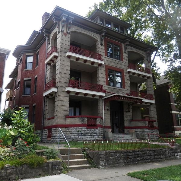 Large historic brick apartment building with balconies and stone accents.