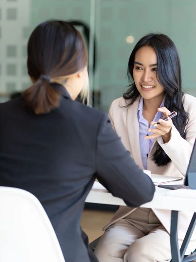 Two women having a professional discussion at an office desk.