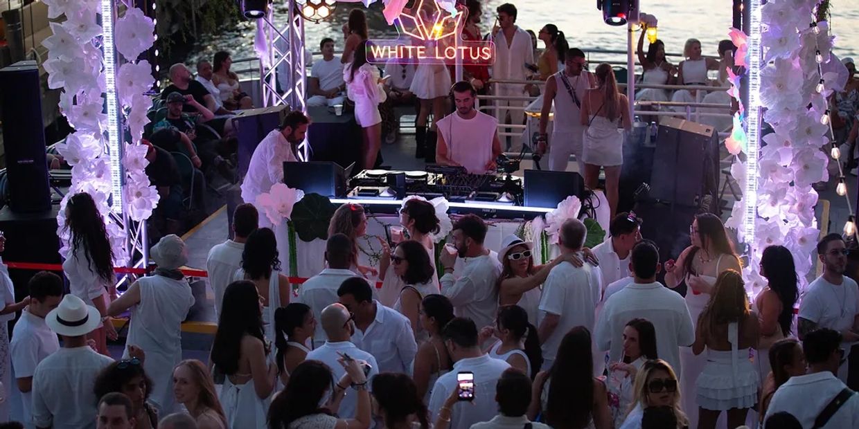 Crowded white-themed party with DJ.