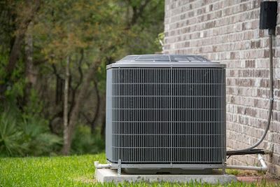 Outdoor air conditioning unit next to a brick house.