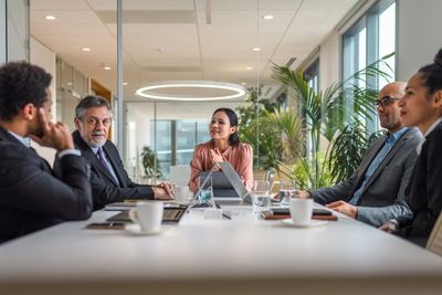 Group of M&A Advisors meeting around a boardroom table discussing a deal.