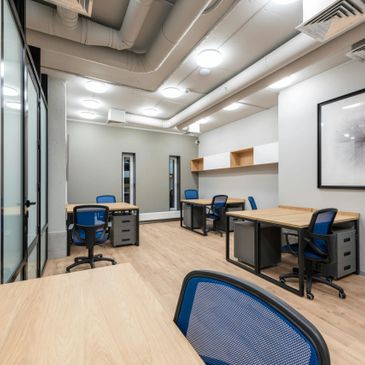 Modern office space with multiple desks and blue chairs.