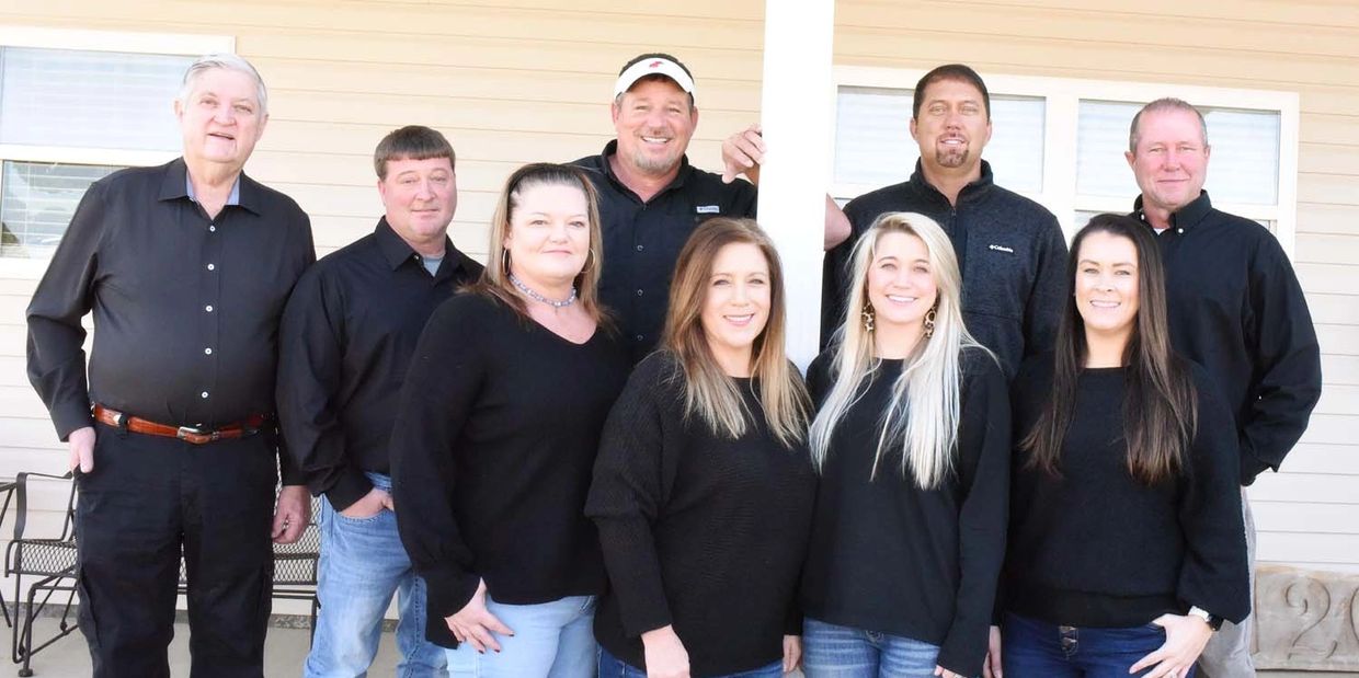 Group photo of nine adults standing outside a building.