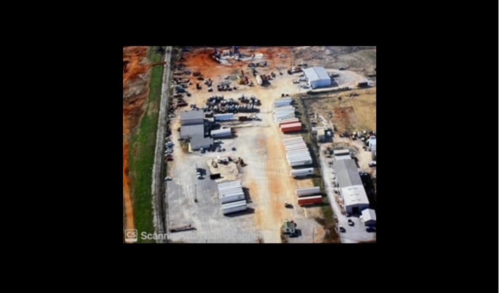 Aerial view of an industrial or construction yard with buildings and containers.