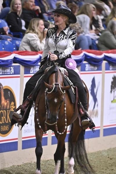 A woman in a decorative outfit rides a horse at a competition.