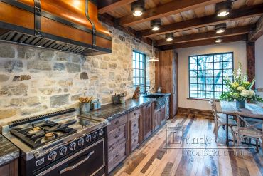 Rustic kitchen with stone walls and wooden beams.