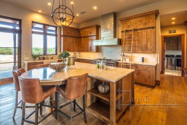 Warm wooden kitchen with island and leather stools.
