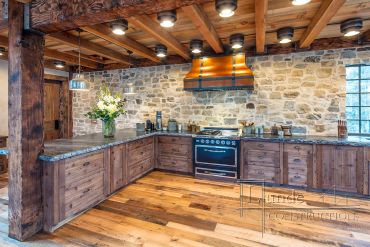Rustic kitchen with wooden cabinets and stone walls.