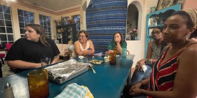 A group of women gathered around a dining table in a cozy room.