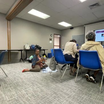 Child sitting on floor playing with a toy in a meeting room.