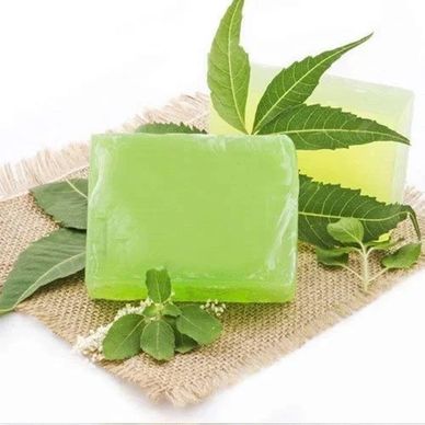 Green herbal soap bars with fresh neem leaves on a burlap cloth.