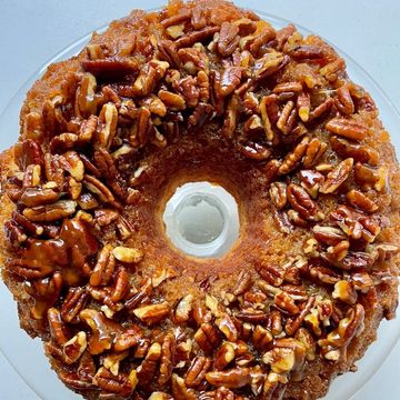 A bundt cake topped with glazed pecans.