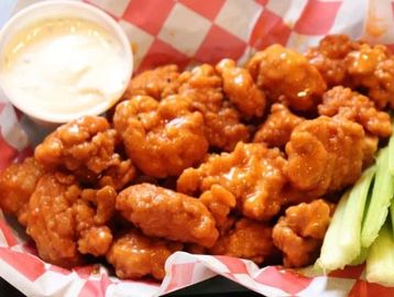 Buffalo cauliflower bites with dipping sauce and celery sticks.