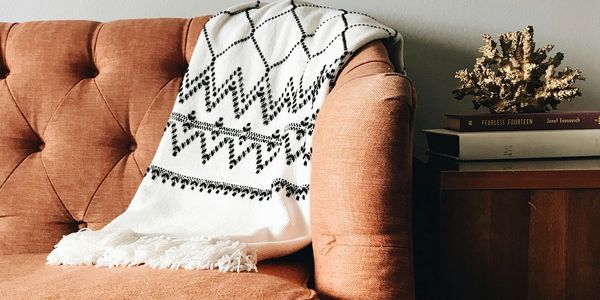 Cozy couch with patterned white blanket and books on a side table.