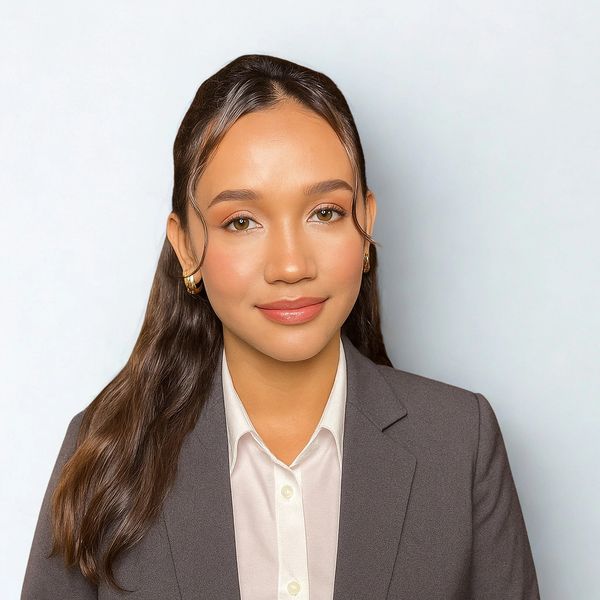 Professional woman wearing a gray blazer and white shirt, smiling gently.