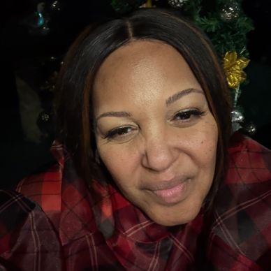 Woman in a red plaid shirt smiling softly.