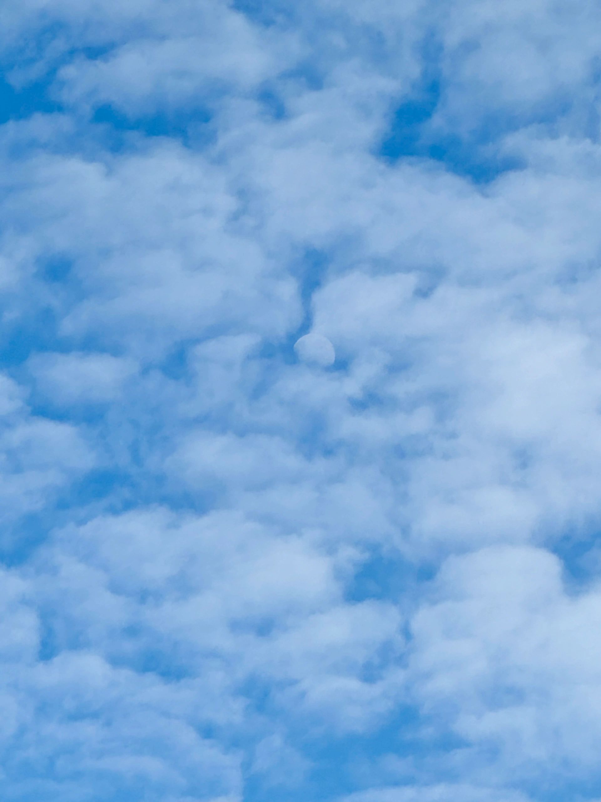 Blue sky with scattered clouds and a faint moon.