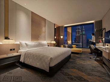 Luxurious hotel room with a king-sized bed and city view at night.
