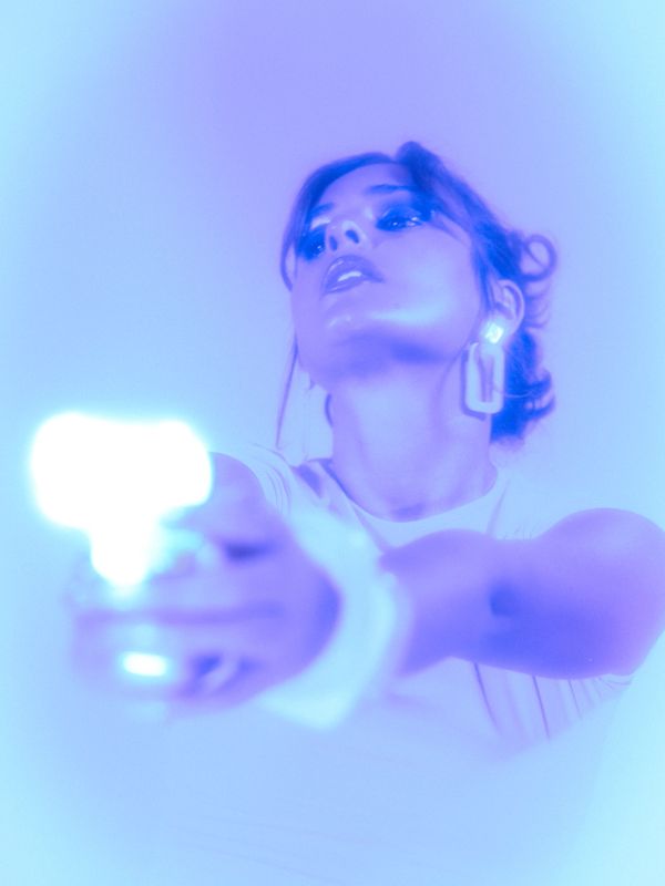 Woman aiming a glowing gun with intense blue lighting.