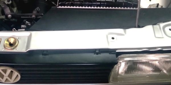 Close-up of a Volkswagen car front with a headlight and emblem.