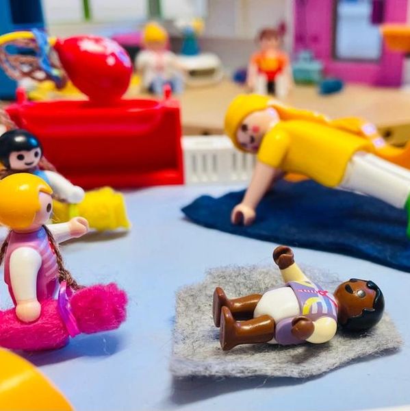Toy figures playing and lying on a miniature playground setup.