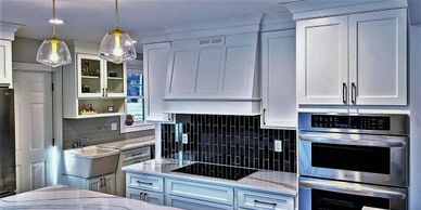 kitchen with white cabinets, crown molding black subway tile over the stovetop 