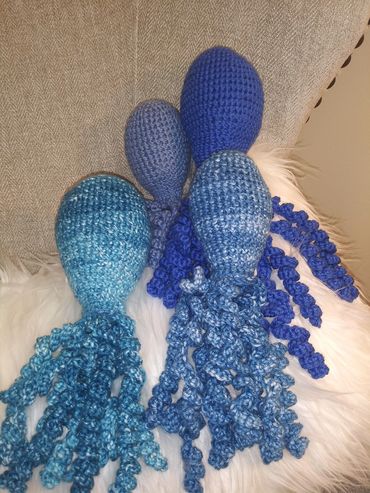 Handmade crocheted blue jellyfish toys with curly tentacles.