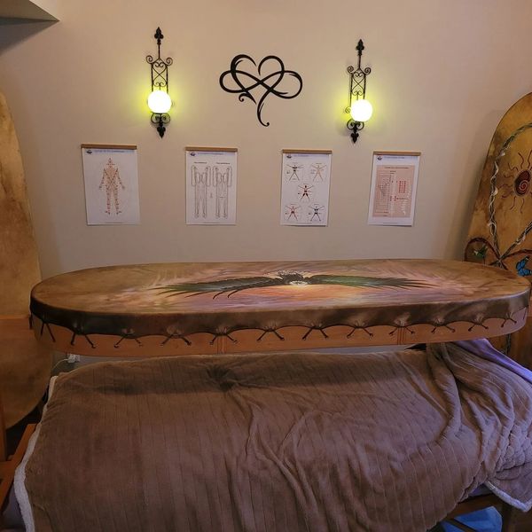 Decorative drum displayed above a massage table in a cozy room.