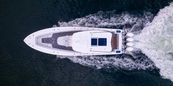 A white yacht cruising on dark water, viewed from above.