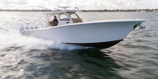 A sleek white motorboat speeding across the water with one person onboard.