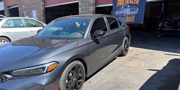 Gray Honda sedan parked outside an auto shop with a Pro Dealer banner.