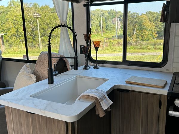 Modern kitchen sink with tall black faucet and window view.