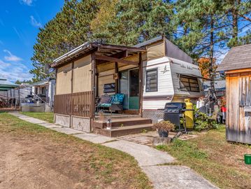 Trailer home with a small porch and outdoor seating.