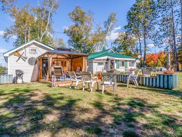 Cozy backyard with chairs and two small buildings.