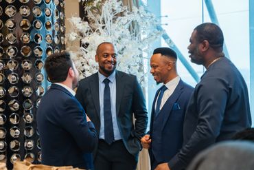 Four men in suits having a lively conversation indoors.