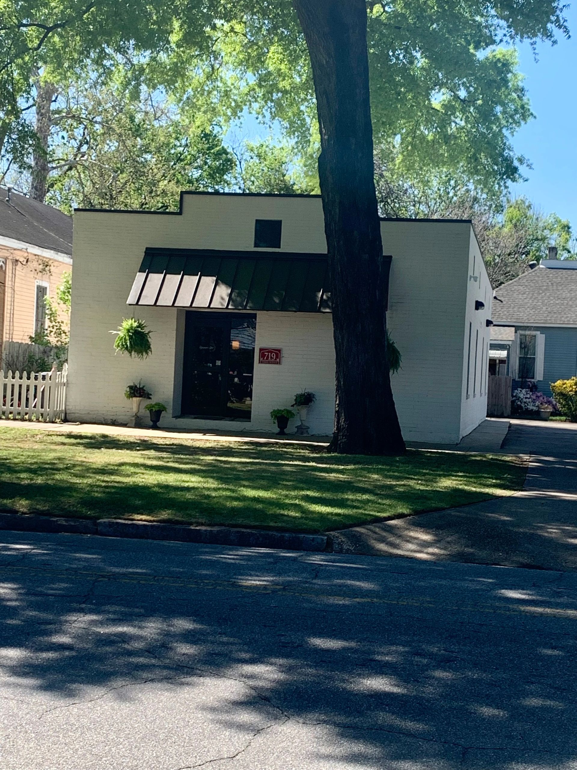 White brick building with dark awning off the front. 