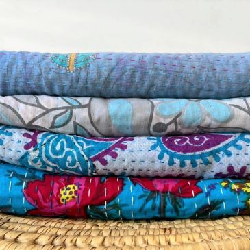 Stack of colorful patterned quilts.