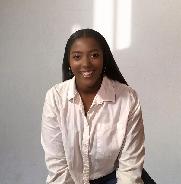 Smiling woman in a white shirt against a light wall.