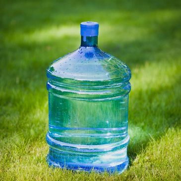 Large blue water jug sitting on green grass.