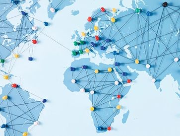 A world map with colorful pins connected by strings representing global networks.