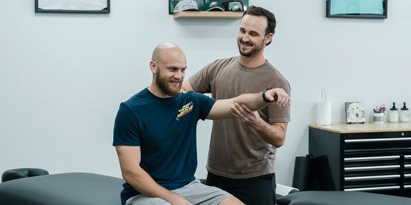 Dr. Michael Krufka using a manual therapy technique, "pin and stretch" on a patient's left shoulder.