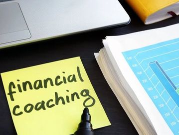 Sticky note with 'financial coaching' beside documents and laptop.