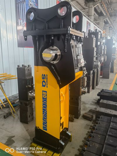 Industrial hydraulic breaker tool in a factory setting.