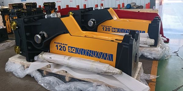 Two Soosan 120 SQ hydraulic breakers on wooden pallets in a warehouse.