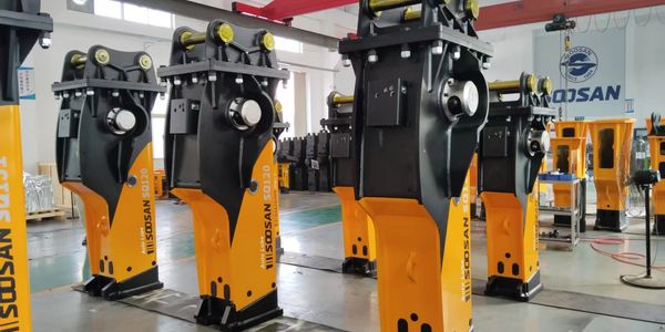 Industrial yellow and black heavy machinery parts lined up indoors.