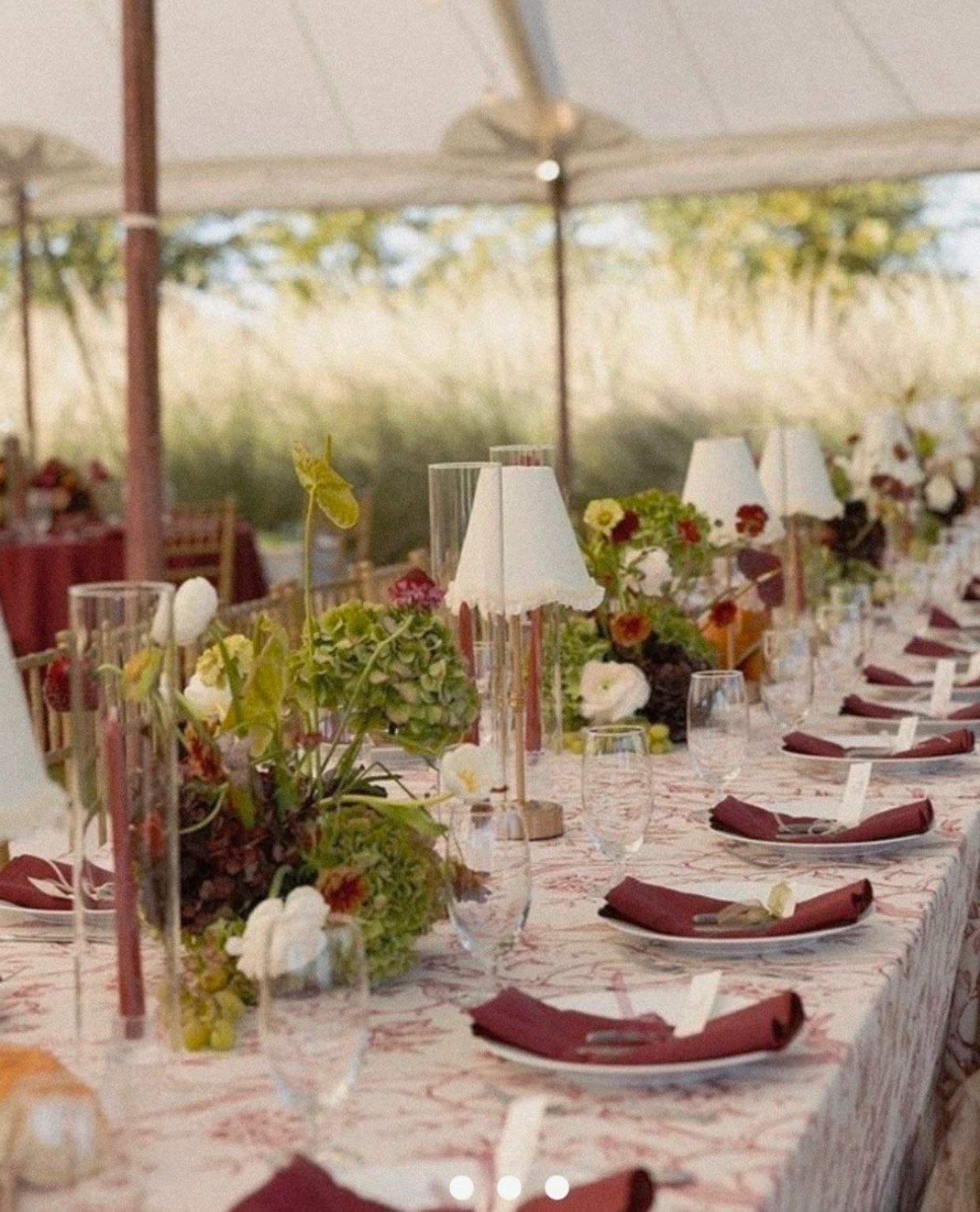 Elegant outdoor dining setup with flowers and burgundy napkins.