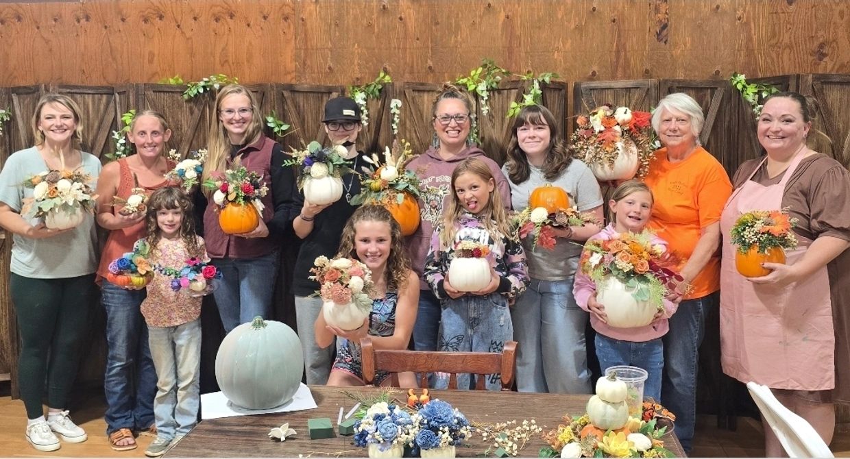 Group of people showing fall-themed floral pumpkin arrangements.