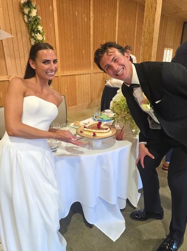 Bride and groom smiling with a cake at their wedding.