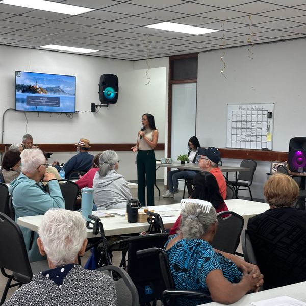 A woman speaks to an audience in a community meeting room.