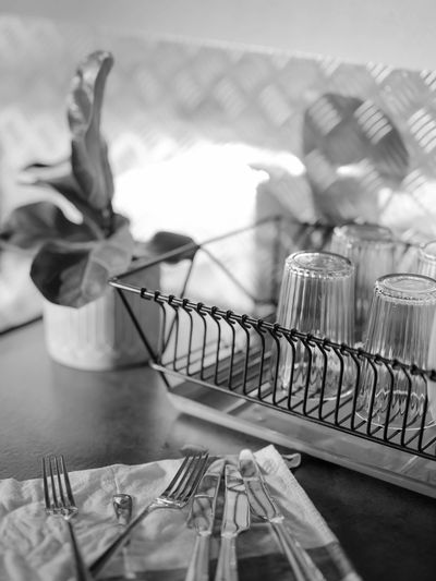 A monochrome scene with clean glasses drying and cutlery on a napkin.